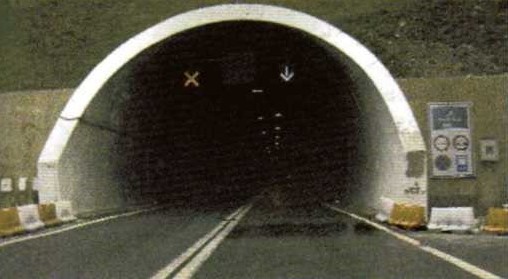 Slika uz pitanje: Što se ne smije činiti vozilom tijekom vožnje kroz tunel u situaciji kao na slici?