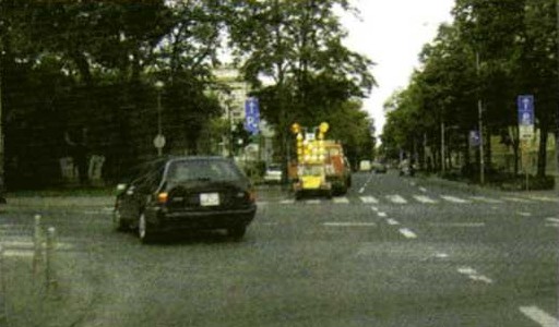 Slika uz pitanje: Kojom prometnom trakom vozač obavlja skretanje ulijevo iz ceste s jednosmjernim prometom u situaciji kao na slici?
