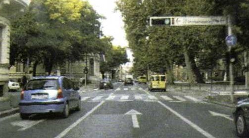 Slika uz pitanje: Vozite u situaciji kao na slici. Što smijete vozilom činiti, a u skladu s prometnim znakovima, prometnim svjetlima i oznakama na kolniku?