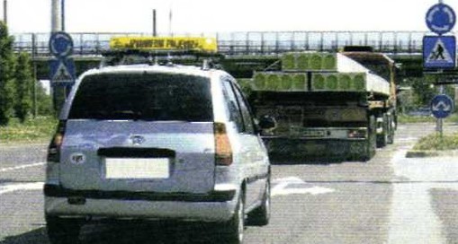 Slika uz pitanje: Kako trebate postupiti kada sustignete vozilo kojim se obavlja izvanredni prijevoz, u situaciji kao na slici?