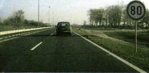 Slika uz pitanje: Što treba činiti vozač za pravodobno uočavanje prometnog znaka i postupanje tijekom vožnje u situaciji kao na slici?